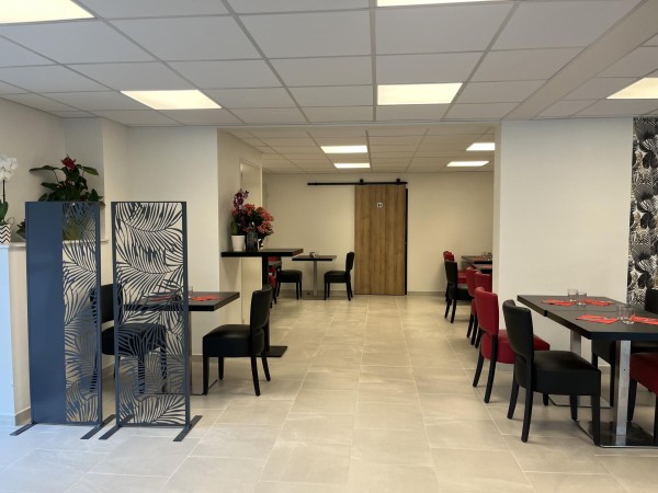 Entrée de la pizzeria, aérée, donnant sur des tables