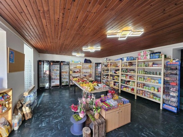 Intérieur de l'épicerie, rayonnages ouverts, étagères et ilot central en bois bien garnis