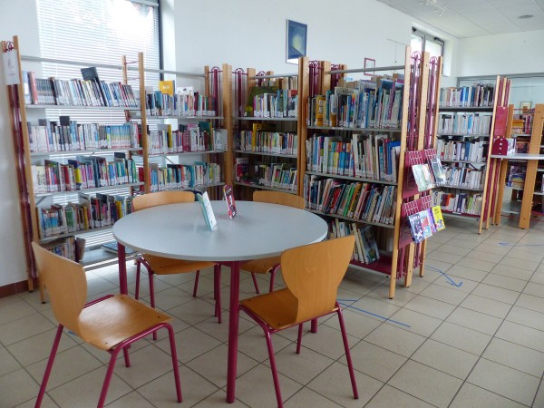 La médiathèque a plusieurs rayonnages et une table pour 4 personnes