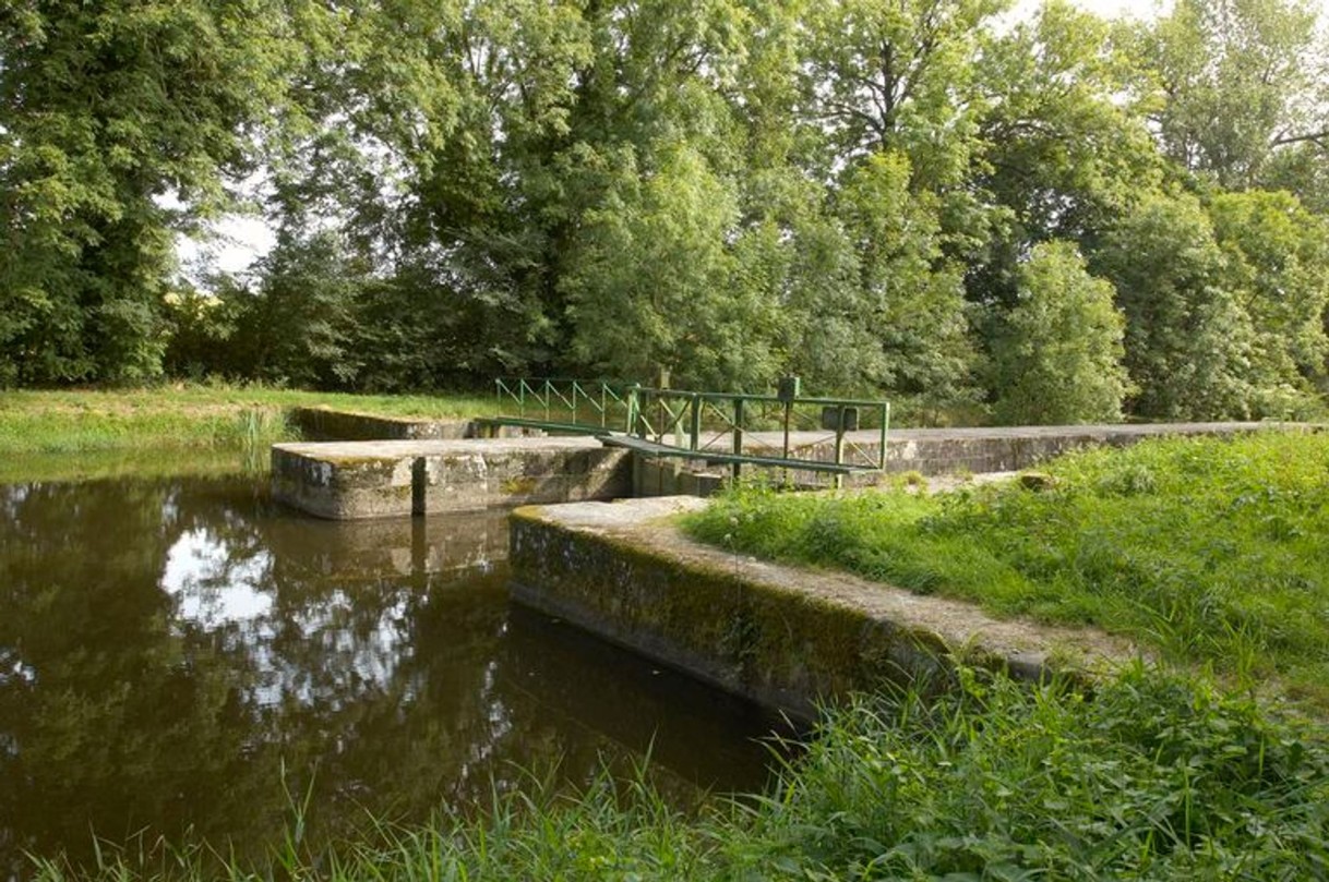 écluse du canal de Nantes à Brest, vue depuis l'amont avec zones en herbe et arbres.